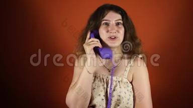 女人在橙色背景下打<strong>电话</strong>。 女执话筒，<strong>座机电话</strong>.. 女人在说话